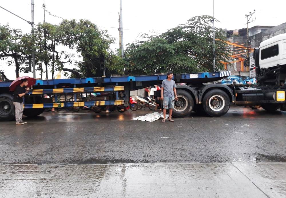 Korban (diblur) tewas oleh tronton dalam kecelakaan di Jalan Gatot Subroto, Jatiuwung, Kota Tangerang, hendak dievakuasi warga setempat.