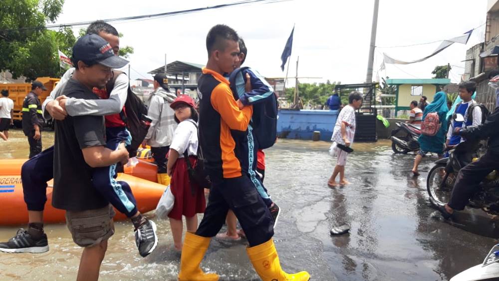 Petugas BPBD Kota Tangerang membantu masyarakat yang ingin menyebrang melewati akses Jalan Regency yang banjir di Kecamatan Periuk, Kota Tangerang.