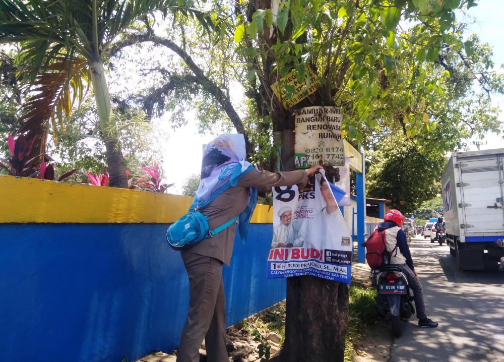 Petugas melakukan pencopotan alat peraga kampanye (APK) yang pemasangannya dinilai melanggar di wilayah Tangsel.	