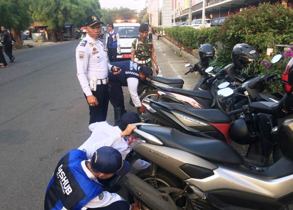 Petugas Dishub Kota Tangerang saat menertibkan pengendara roda dua yang parkir sembarangan di bahu jalan Kota Tangerang.