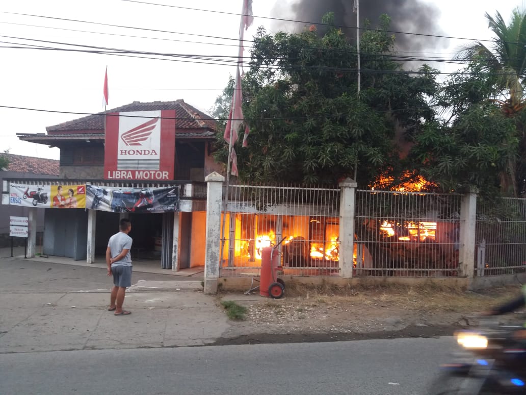 Tampak petugas pemadam kebakaran berusaha memadamkan api yang berkobar di showroom sepeda motor di Kampung Babakan Tengah, RT 01/02, Kelurahan Babakan, Kecamatan Legok, Kabupaten Tangerang.