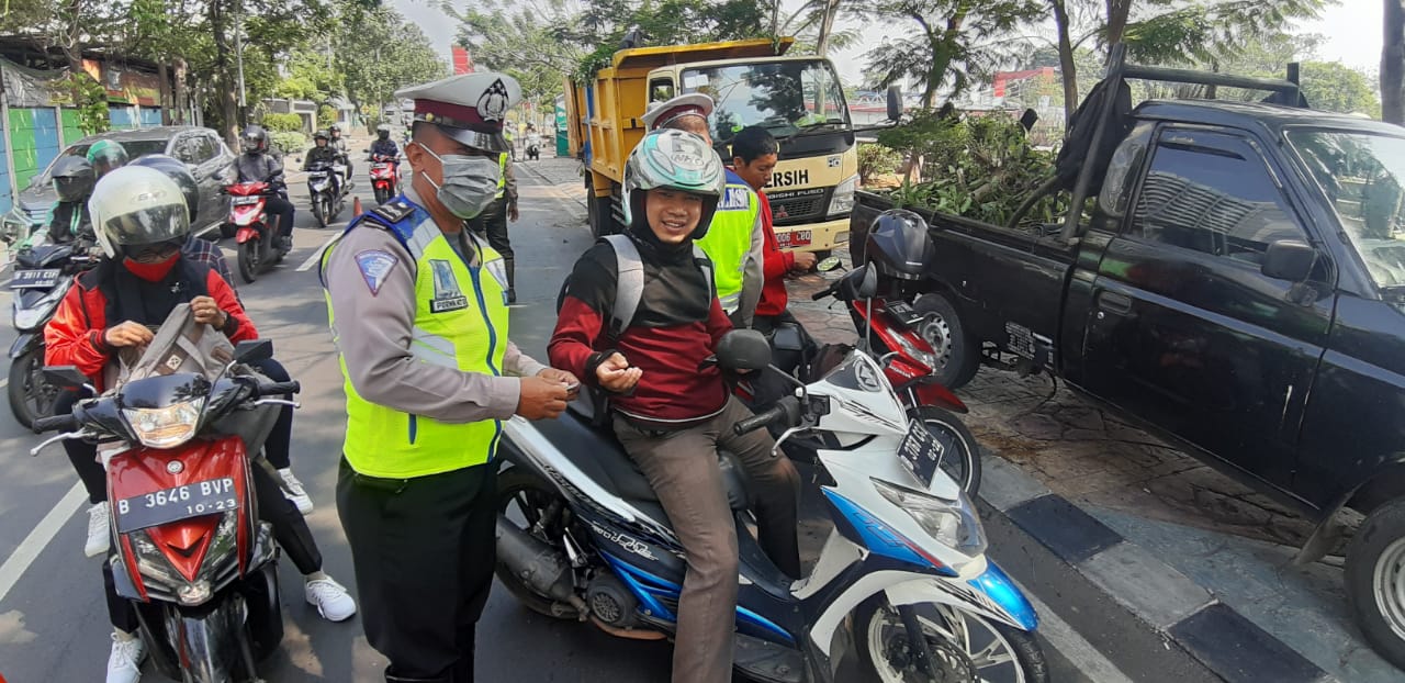 Terlihat Polisi saat memberhentikan pengendara motor untuk memeriksa kelengkapan surat-surat dan kelengkapan lainnya dari pengguna jalan tersebut.