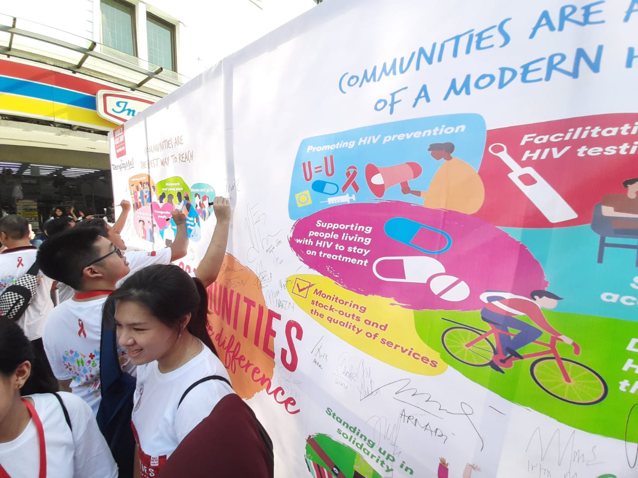 Suasana para komunitas masyarakat saat tanda tangan di benner dalam rangka dukungan kegiatan Memperingati Hari AIDS Sedunia di pelataran perkantoran Tangcity, Kota Tangerang, Minggu (1/12/2019).