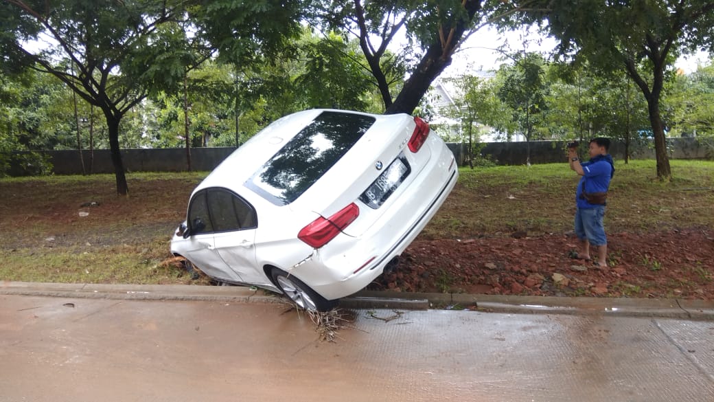 Tampak mobil BMW berwarna putih terseret arus banjir di Perumahan Laverde, Kecamatan Serpong, Kota Tangerang Selatan, Rabu (1/1/2020).