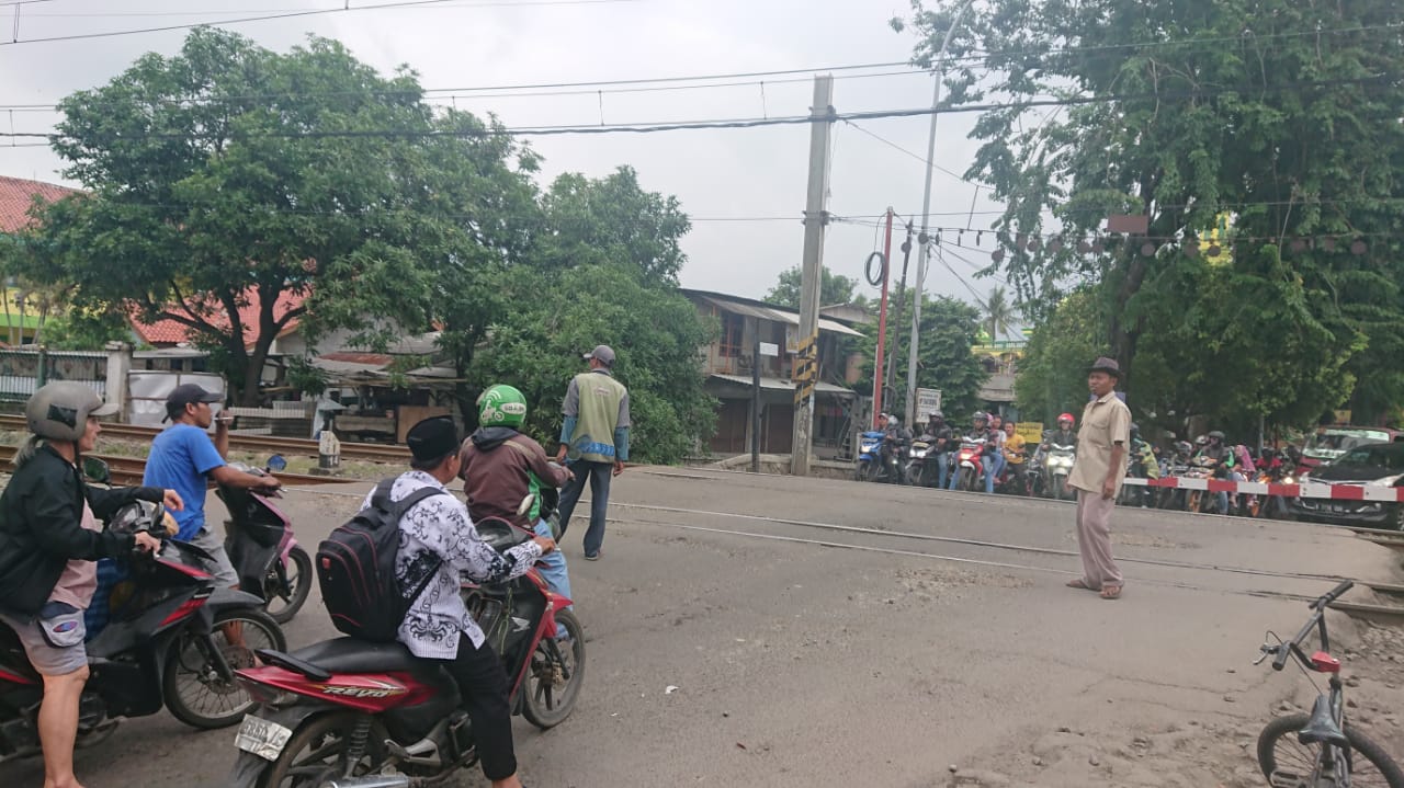 Para pengendara sepeda motor dan mobil di Jalan Maulana Hasanudin sedang menunggu kereta melintas.