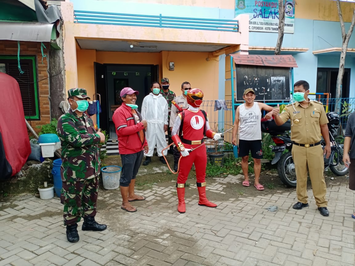 Pria berkostum power ranger sedang menyemprotkan disinfektan di lingkungan RT3/1 Cipondoh Makmur, Selasa (24/3/2020).