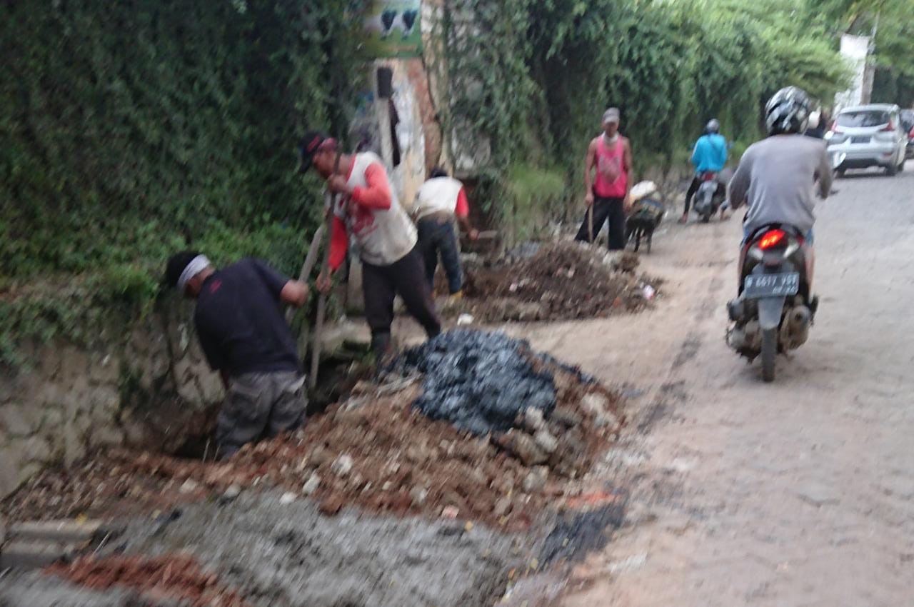 Tampak para pekerja sedang memperbaikan jalan yang rusak di Perumahan Taman Royal, Kota Tangerang, Kamis (26/3/2020).