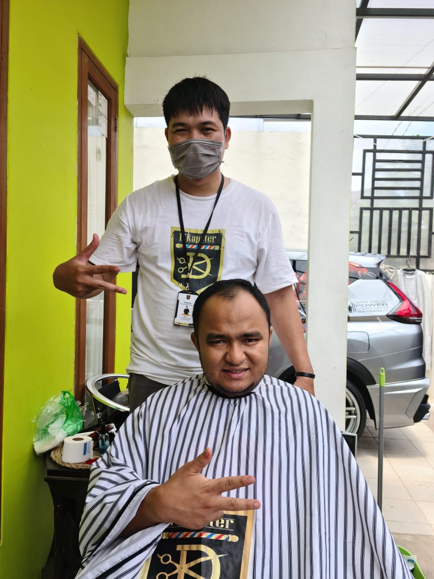 Dkapster saat mencukur rambut konsumen.