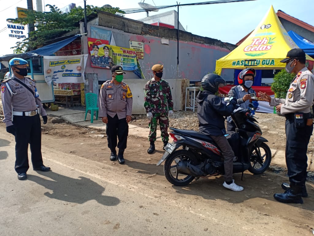 Petugas gabungan TNI, Polri, Dinas Perhubungan, Satpol PP, Badan Penanggulangan Bencana Daerah dan petugas kesehatan saat memberikan arahan bagi pengendara yang tidak mengikuti aturan PSBB di Jalan Raya Serang, Bitung, Kabupaten Tangerang.