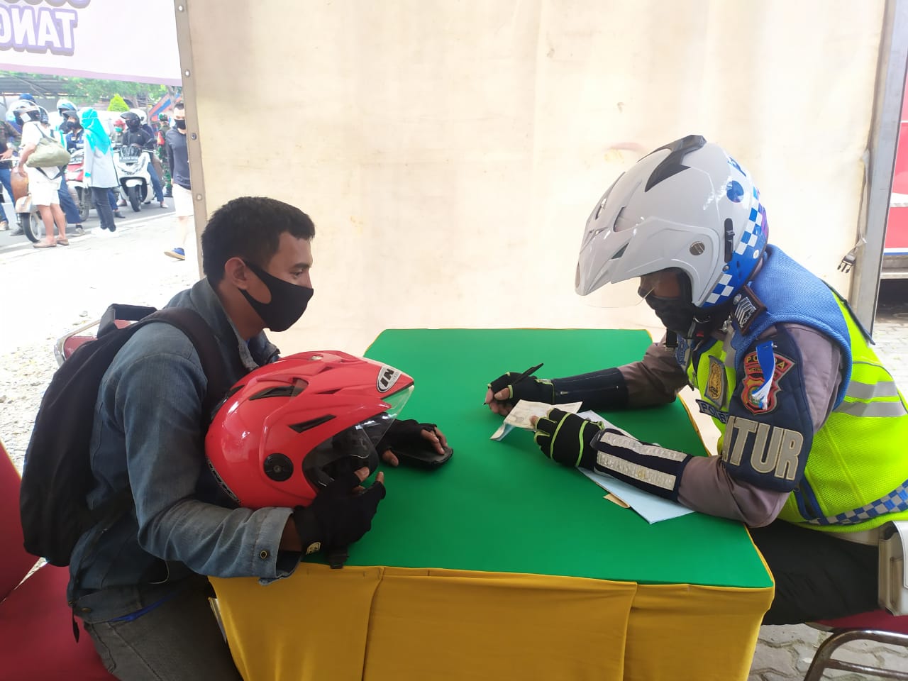 Polisi saat memberikan surat teguran kepada salah satu pelanggar di Posko Check Point Sandratek, Rempoa, Ciputat Timur, Tangerang Selatan.