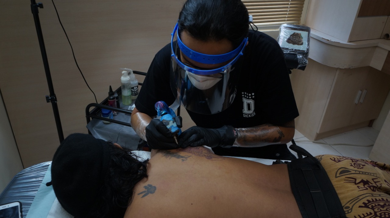 Seniman tato di NiceArt Tattoo Studio, Kota Tangerang, mengenakan masker dan face shield untuk menjamin kesehatan pelanggan saat pandemi COVID-19, Rabu (24/6/2020).
