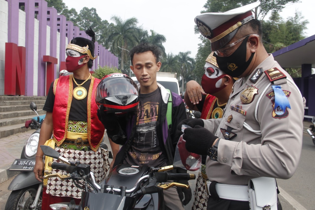 Menggunakan kostum tokoh pewayangan, Personel Satlantas Polresta Tangerang mengedukasi pengendara bermotor di Jalan Pemda Tigaraksa, Senin (27/7/2020).