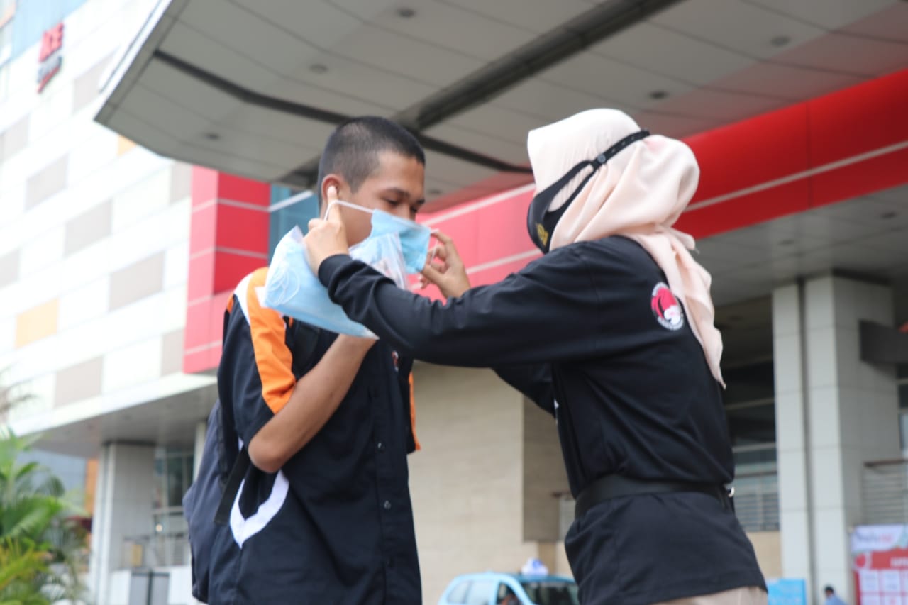 Polwan cantik dari Satnarkoba Polres Metro Tangerang Kota saat memberikan masker gratis kepada warga, Kota Tangerang, Selasa (18/7/2020).