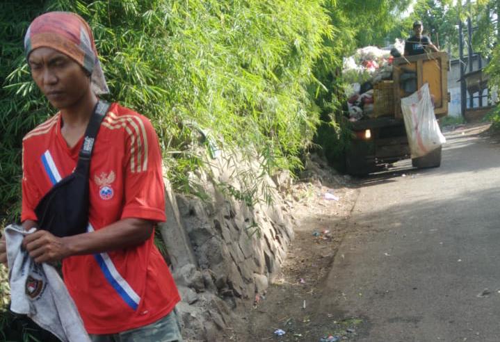 Petugas kebersihan saat menaiki sampah yang berserakan di pinggiran jalan ke dalam se unit Truk sampah, Kota Tangerang, Rabu (25/11/2020).