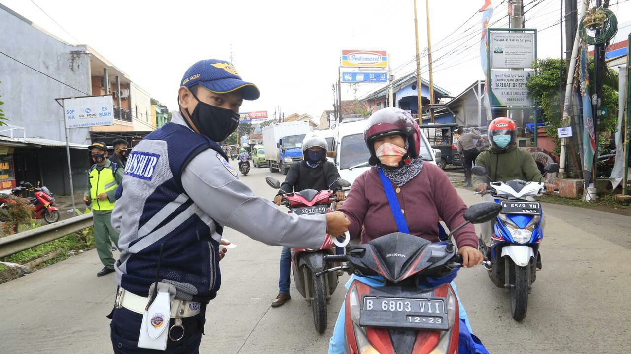 Petugas dishub saat memberikan masker secara gratis kepada pengendara motor dalam program kegiatan Tangsel Bermasker, Tangsel, Kamis (4/2/2021).
