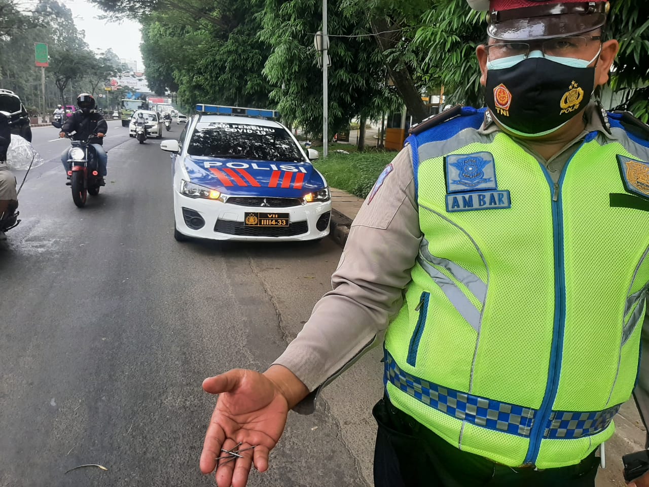 Petugas kepolisian saat memegang beberapa jumlah paku di Jalan Jenderal Sudirman, Kecamatan Tangerang, Kota Tangerang, Senin (24/5/2021).