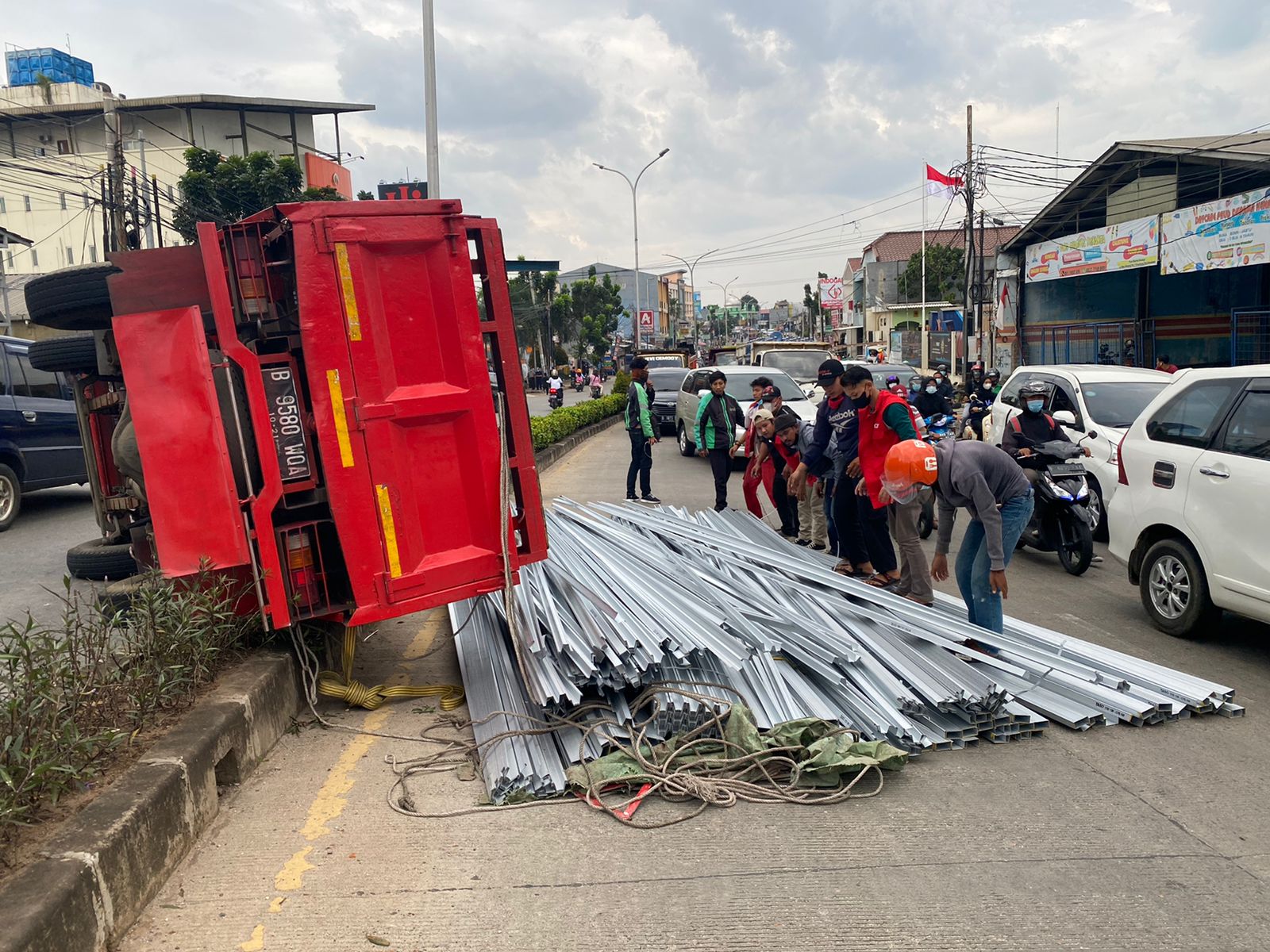 Satu unit truk berwarna merah pengangkut baja ringan terguling di Jalan Raya Siliwangi, Pamulang, Kota Tangerang Selatan pada Senin, 6 September 2021 petang.