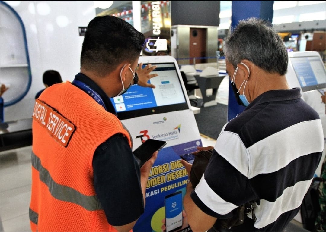 calon penumpang pesawat saat dipandu petugas bandara scan barkot QR di aplikasi PeduliLindungi.
