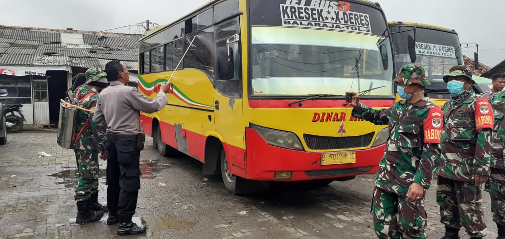 Cegah penularan COVID-19, bus yang terparkir di terminal Kresek, Kabupaten Tangerang disemprot disinfektan oleh personel kepolisian dan TNI, Minggu (22/3/2020).