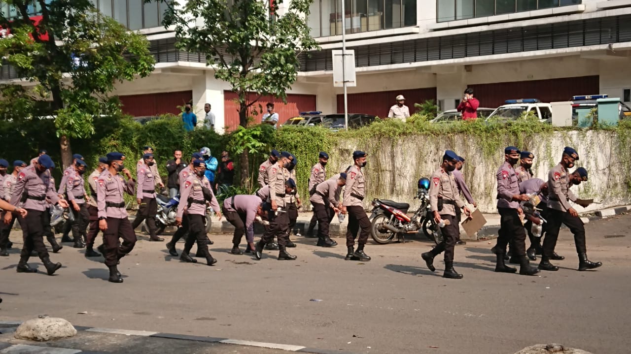 Para petugas Kepolisian saat membersihkan sampah bekas aksi buruh di kawasan Tangcity Mal, Cikokol, Kota Tangerang.
