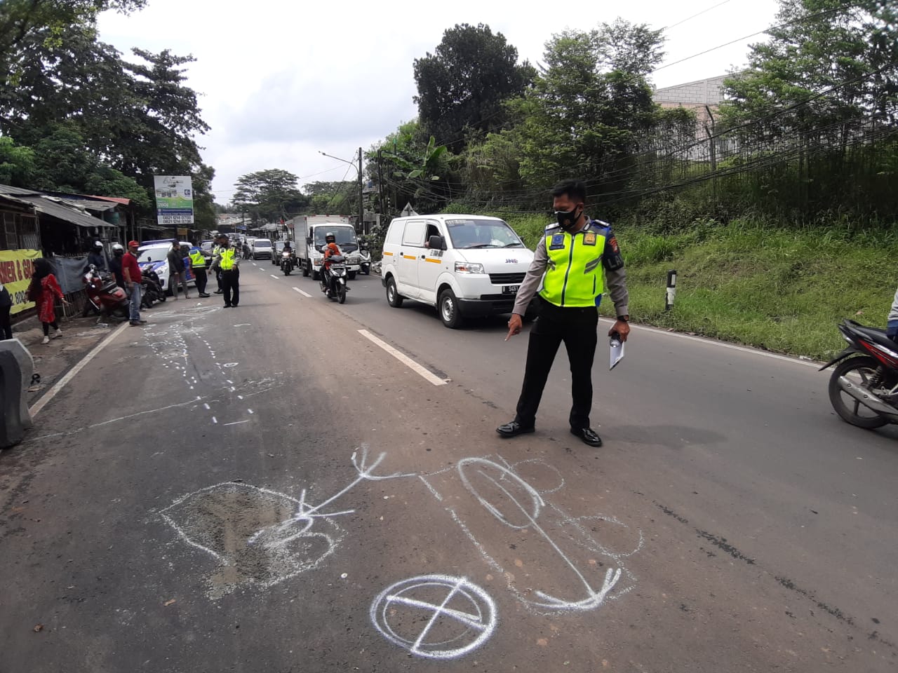 Seorang Anggota kepolisian menunjuk ke arah tempat terjadinya kecelakaan maut hingga merenggut nyawa dua balita di Jalan Pondok Cabe Raya, Pamulang, Tangerang Selatan, Kamis (25/2/2021).